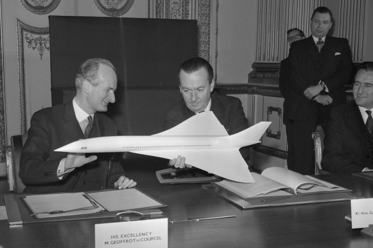 Image: Geoffroy de Courcel, a la izquierda, embajador francés en Londres, y Julian Amery, el ministro de aviación británico, observan un modelo de un avión supersónico propuesto en Lancaster House, Londres, donde firmaron un acuerdo anglo-francés para el desarrollo conjunto de un avión supersónico de pasajeros.