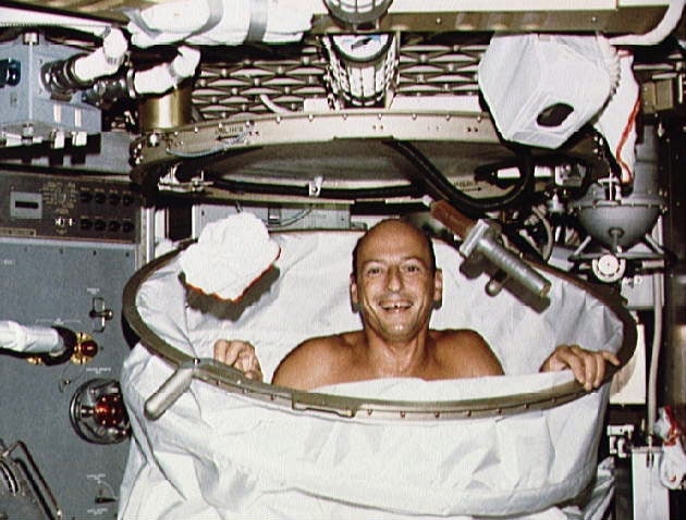 El comandante Conrad de la misión Skylab 2, usando la ducha de la estación espacial (junio de 1973).