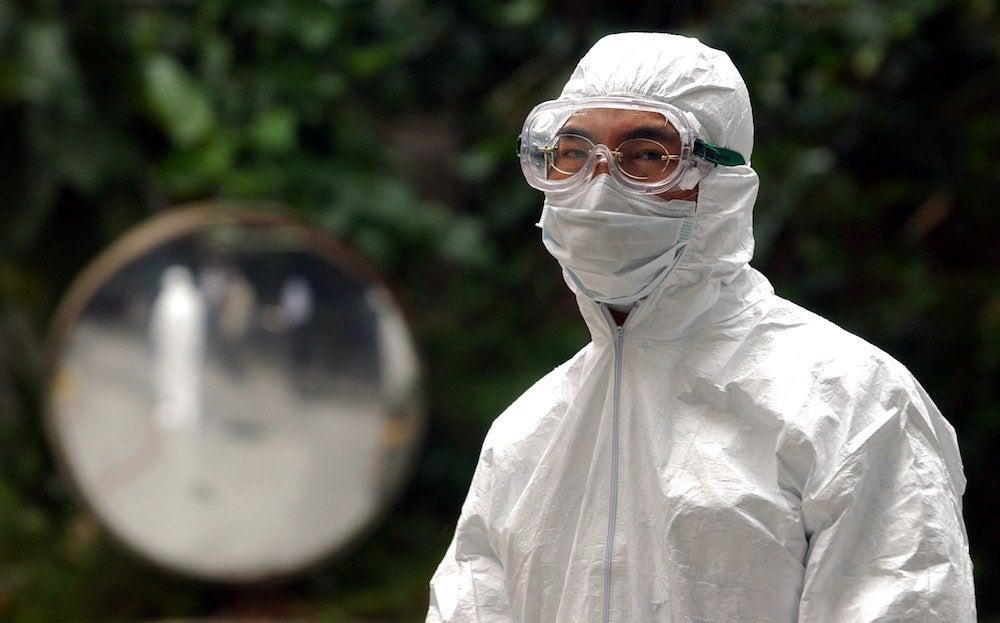 Image: Un trabajador del Departamento de Higiene Alimentaria y Ambiental con un equipo de protección mientras participa en la eliminación de desechos de un complejo de apartamentos infectado