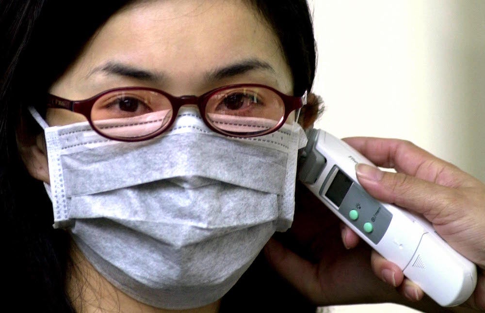 Image: Tomando la temperatura de una mujer a su llegada al aeropuerto internacional de Chiang Kai-shek en Taoyuan, suroeste de Taipei