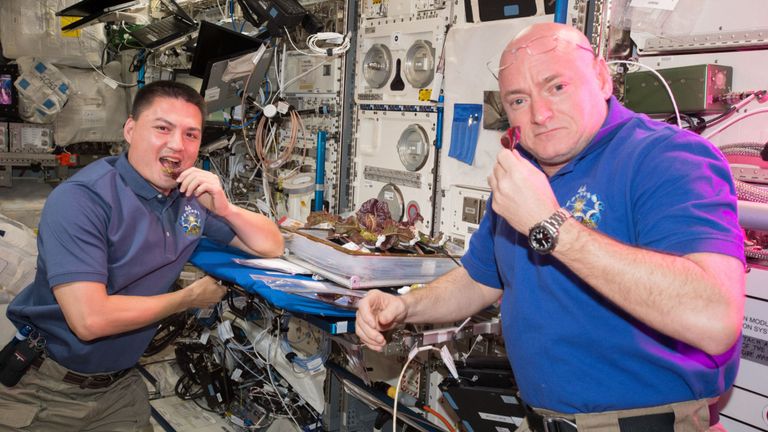 Dos astronautas probando la lechuga sembrada a bordo de la Estación Espacial Internacional.