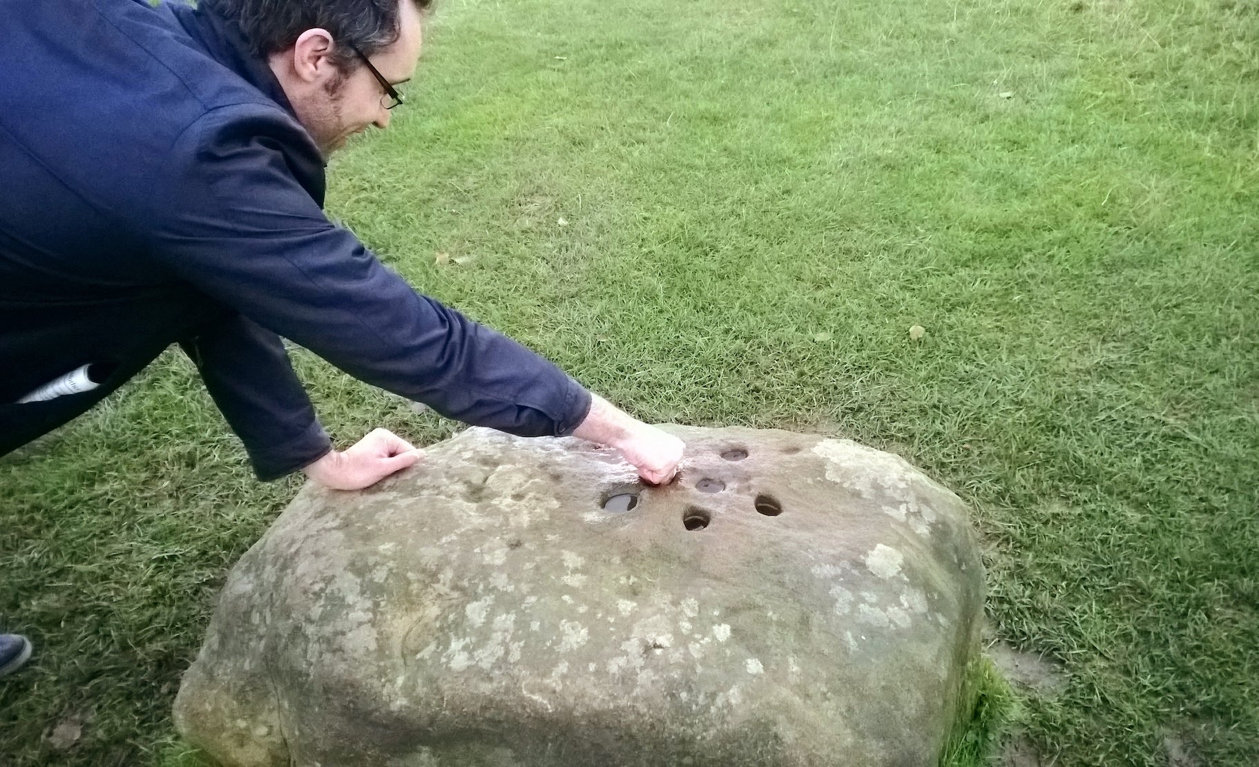 Image: Un turista coloca una moneda en una de las piedras límite de Eyam