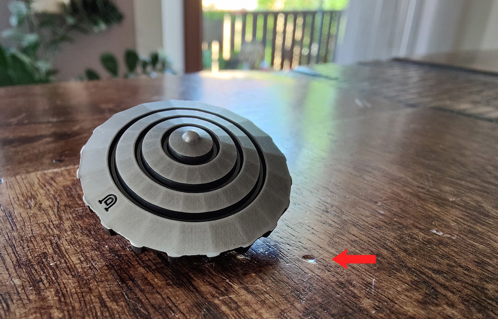 El D20 visto por abajo. al lado, lo que pasa si arrojas esa punta metálica sobre la mesa en vez de girarla.