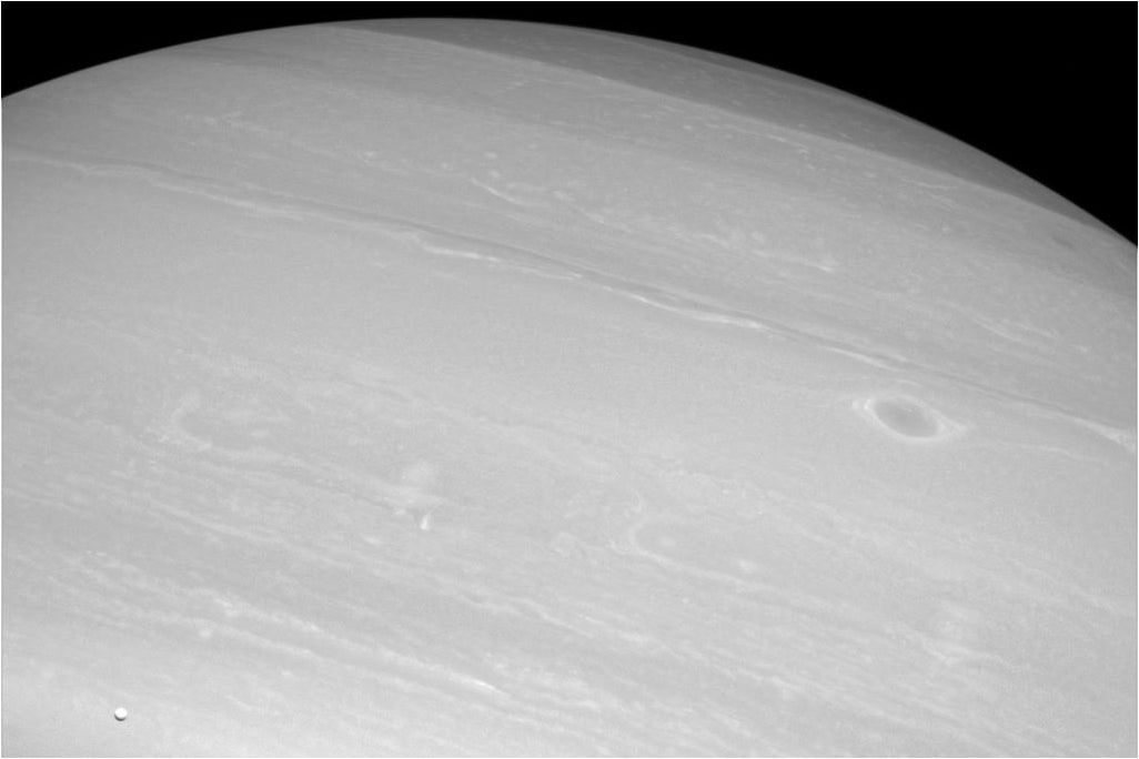 Encélado (abajo a la izquierda) con Saturno de fondo.