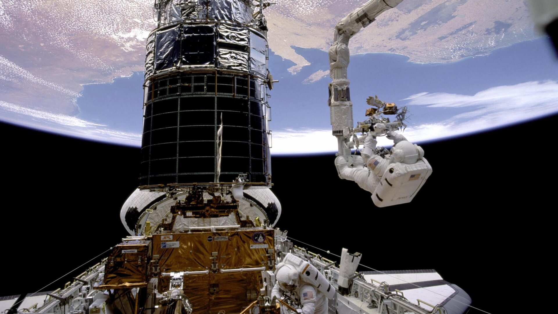 Un astronauta colocando una lente correctora sobre el Telescopio Hubble.