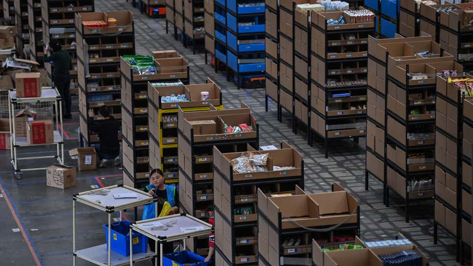 Empleados colocan los productos en estanterías que luego son movidos por robots en el almacén de Cainiao Smart Logistics Network, la filial de logística del gigante del comercio electrónico Alibaba, en Wuxi, provincia de Jiangsu en el este de China