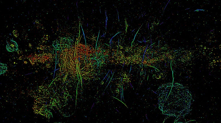 Una imagen multicolor muestra largas rayas verticales de filamentos magnéticos en el núcleo de la Vía Láctea.