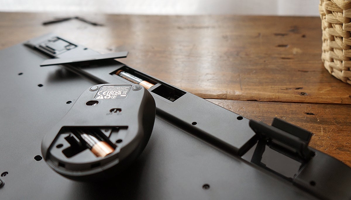 Detalle de los compartimentos para guardar el receptor USB y del doble pie extensible del teclado.