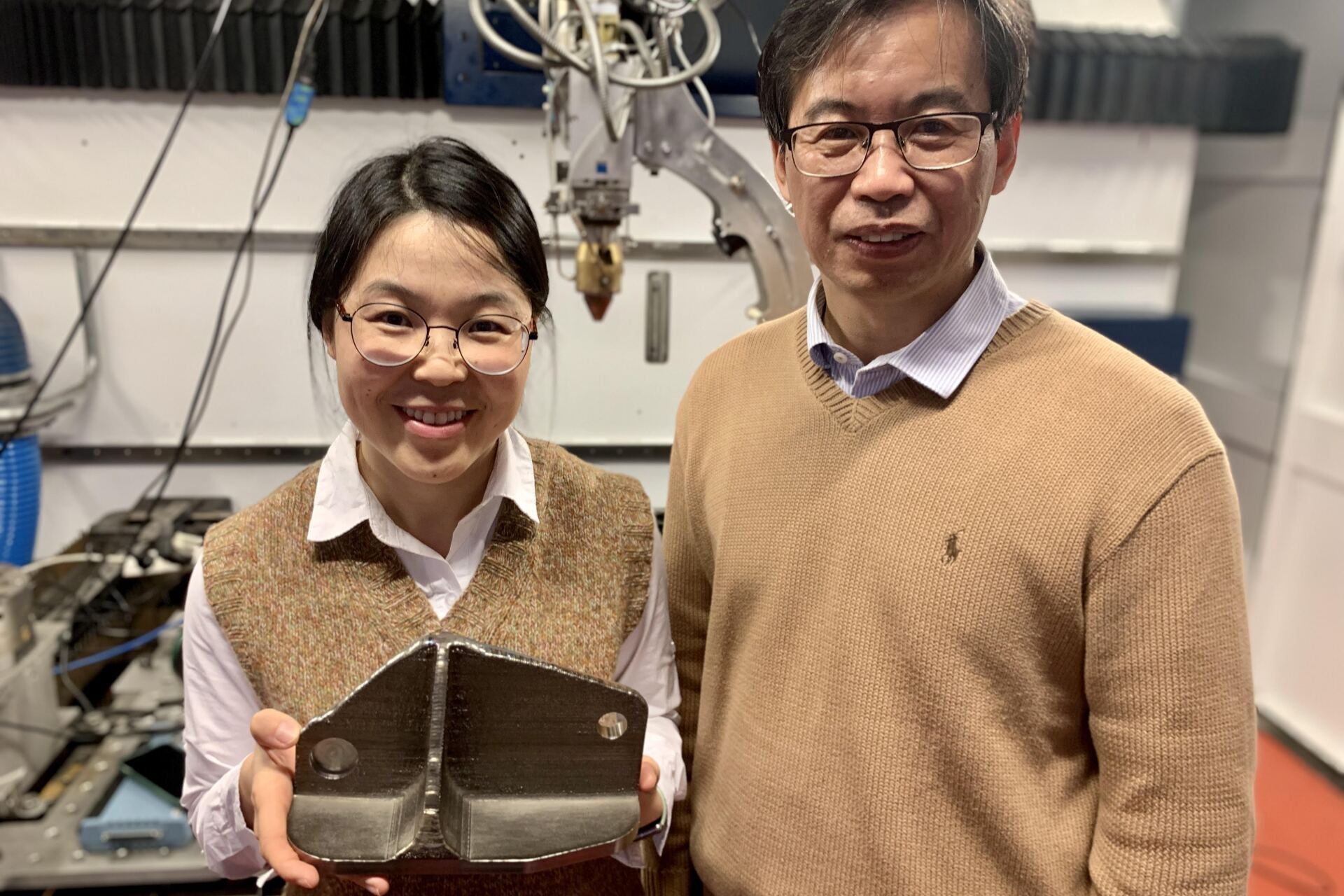 Tingting Song y Ma Qian con una pieza de aleación de titanio creada con la impresora láser 3D que el equipo usó en la Universidad RMIT