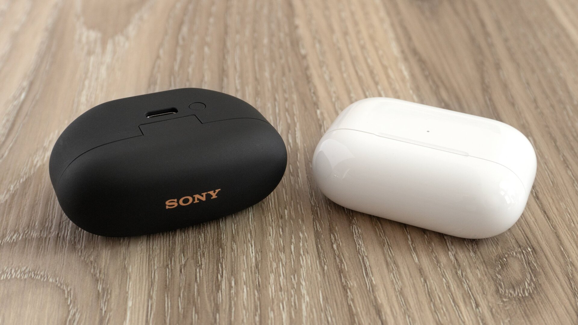 El estuche de carga del Sony WF-1000XM5 (izquierda) es casi idéntico en tamaño al estuche de carga de los AirPods Pro 2 de Apple (derecha), pero se puede cargar utilizando un cable USB-C en lugar de un cable Lightning.