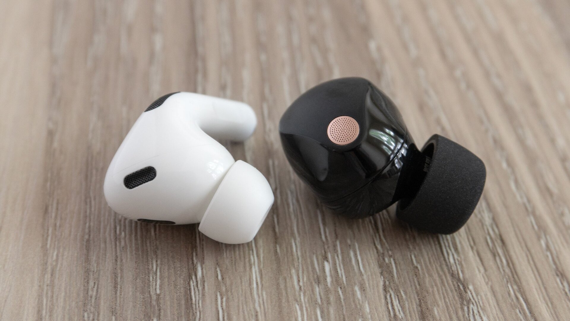 Los Sony WF-1000XM5 (derecha) son un poco más gruesos que los Apple AirPods Pro 2 (izquierda) pero se las arreglan para empacar todos sus  electrónica en un auricular que se coloca justo en el oído.