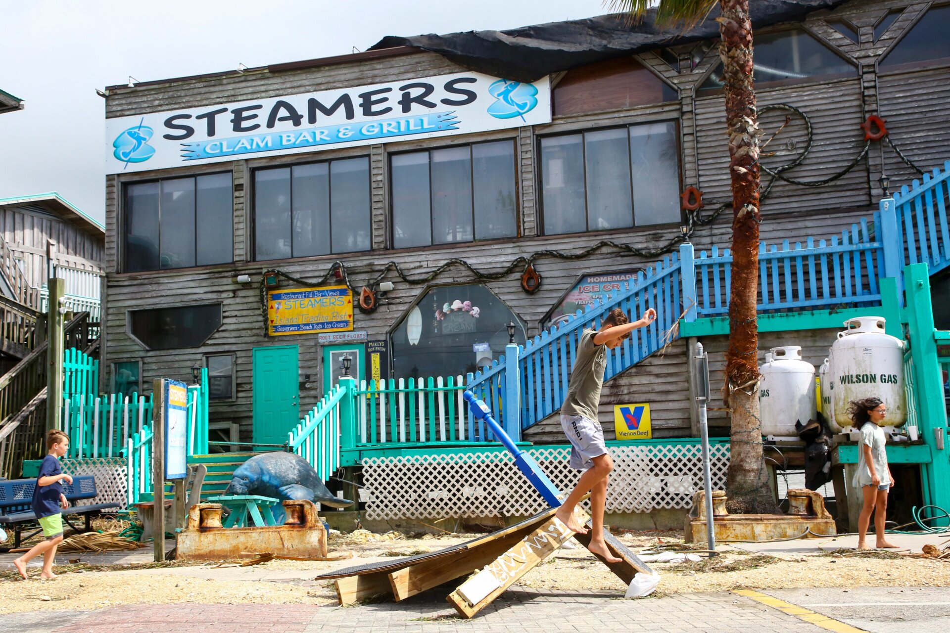 Un lugareño trepa a los escombros afuera de la choza y bar de mariscos Steamers después de que su terraza junto al agua fuera dañada el 30 de agosto de 2023 en Cedar Key, Florida tras el huracán Idalia.