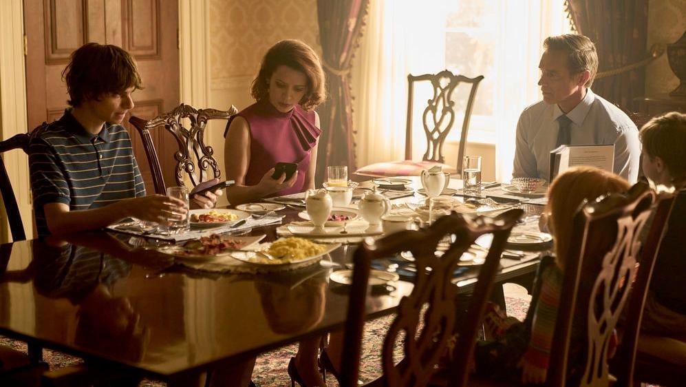 La Primera Familia (incluido Devon Sawa como James Collins, a la derecha) se sienta alrededor de la mesa de desayuno con Chucky en chuky.