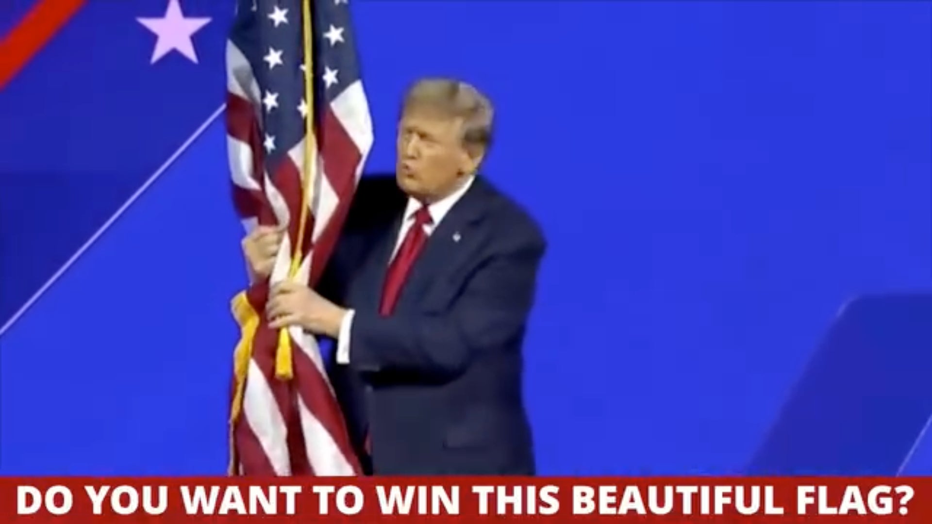 Captura de pantalla de un anuncio de vídeo que se publica actualmente en Facebook que muestra a Trump tocando una bandera estadounidense y ofreciendo a los contribuyentes de la campaña la oportunidad de ganarla. 