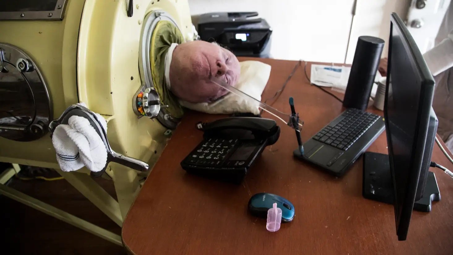 Paul Alexander escribe sus memorias usando un bolígrafo sujeto a un palo.