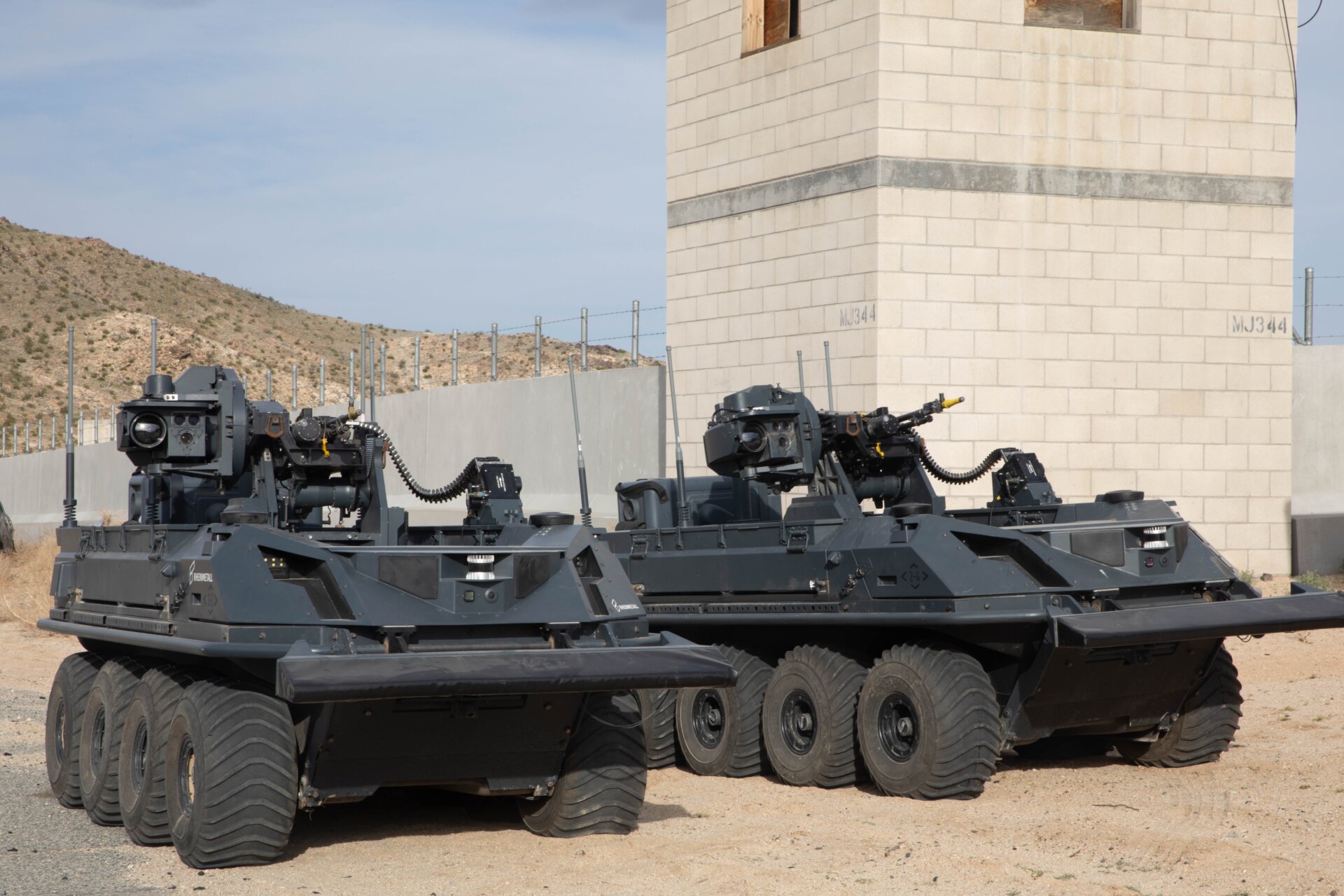 Dos vehículos de transporte británicos, no tripulados, de ocho ruedas, totalmente eléctricos y todo terreno, armados con un sistema de armas autónomo del Grupo de Experimentación y Senderos, proporcionan  apoyo a soldados del Reino Unido desmontados en un entorno urbano como parte de un experimento de integración humana en Fort Irwin, California, 11 de marzo  2024.
