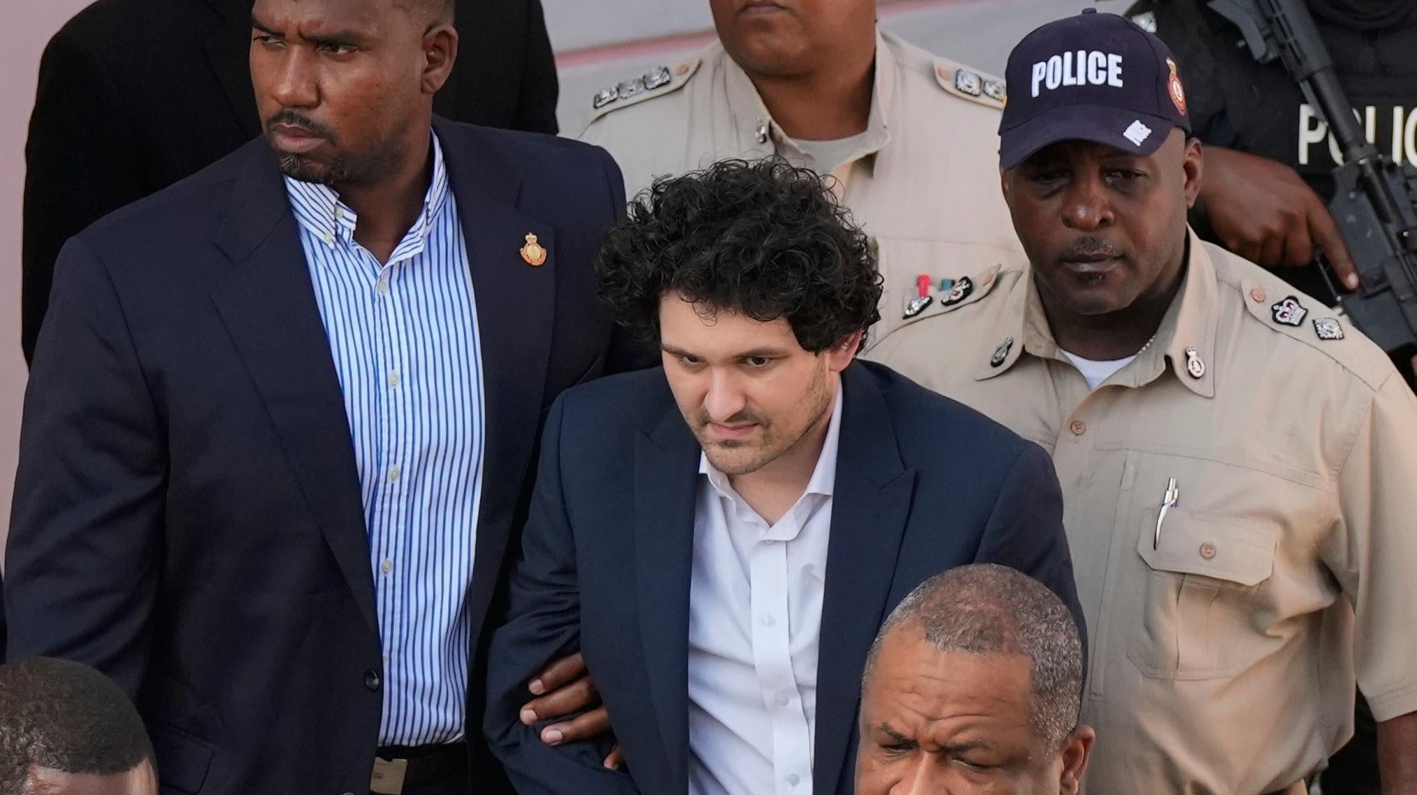 El fundador de FTX, Sam Bankman-Fried (centro), es escoltado fuera de un tribunal en Nassau, Bahamas, antes de ser extraditado a los EE. UU. en diciembre. . 19, 2022.