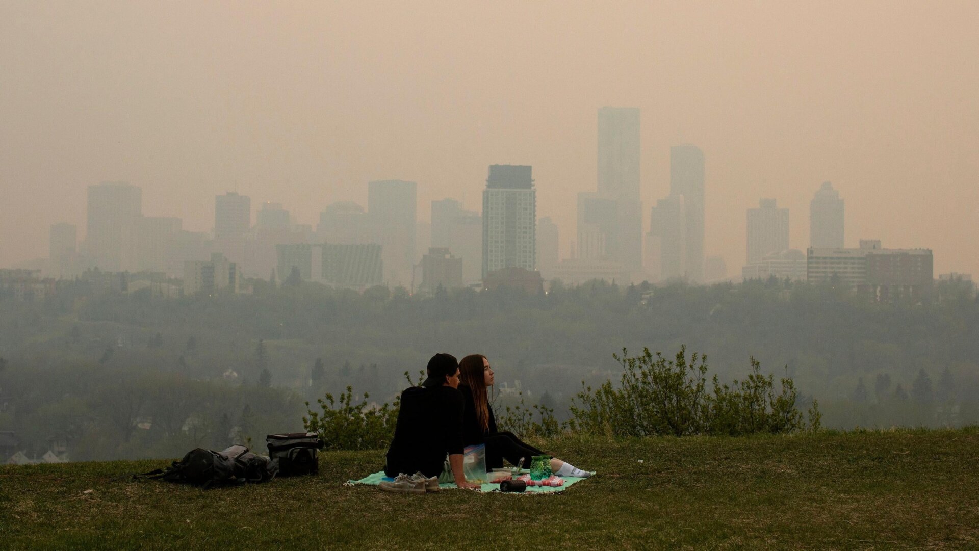 El humo de los incendios forestales cubre la ciudad mientras una pareja hace un picnic en Edmonton, Alberta, el 11 de mayo de 2024.