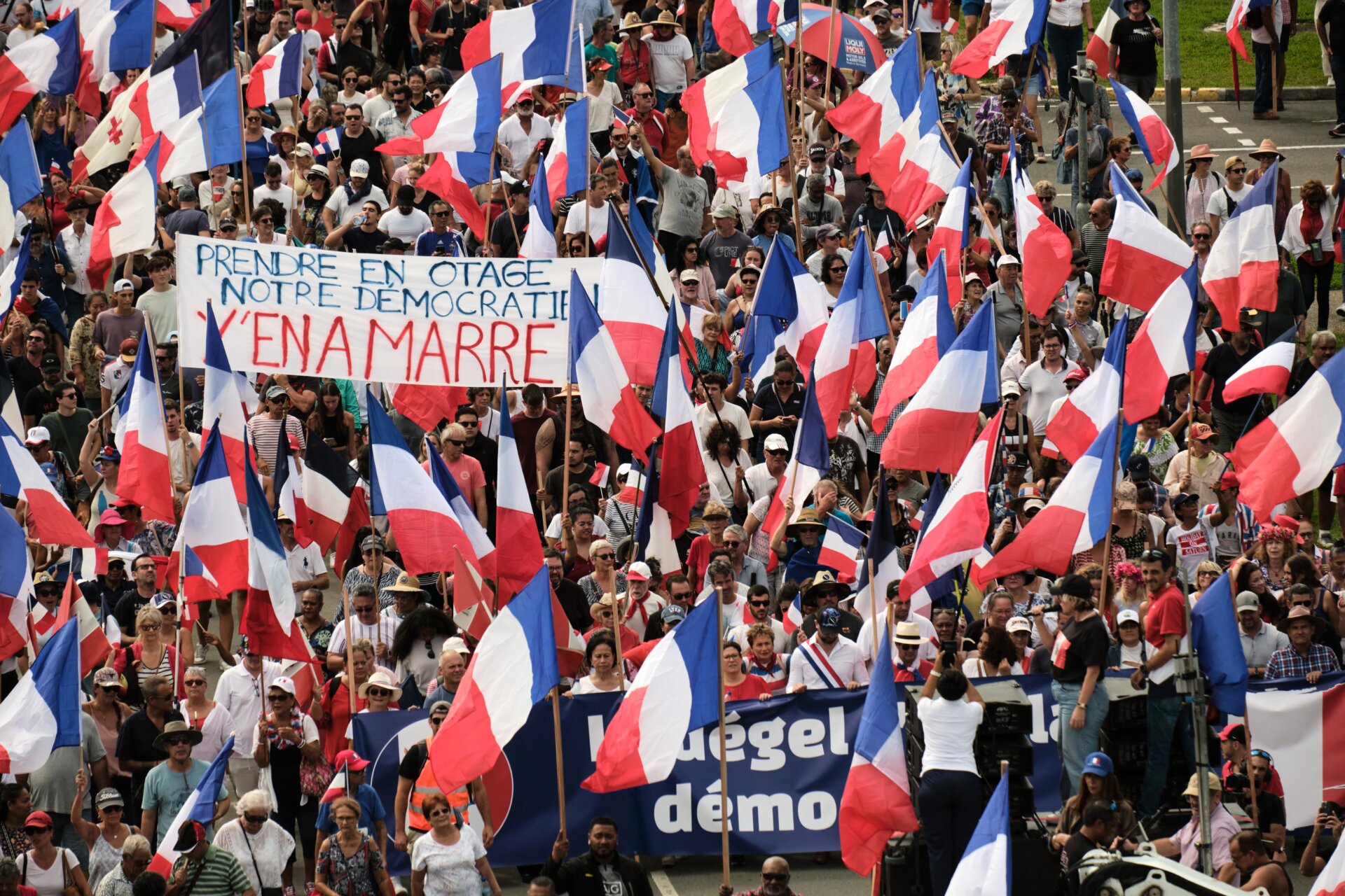 Manifestantes de varios partidos leales ondean banderas nacionales francesas y sostienen una pancarta que dice “Prendre en otage notre democratien y’en a marre” (Quitenles nuestra democracia) mientras marchan durante una manifestación para apoyar la ampliación del electorado para las próximas elecciones provinciales elecciones en Nueva Caledonia, en Noumea, el 13 de abril de 2024. 