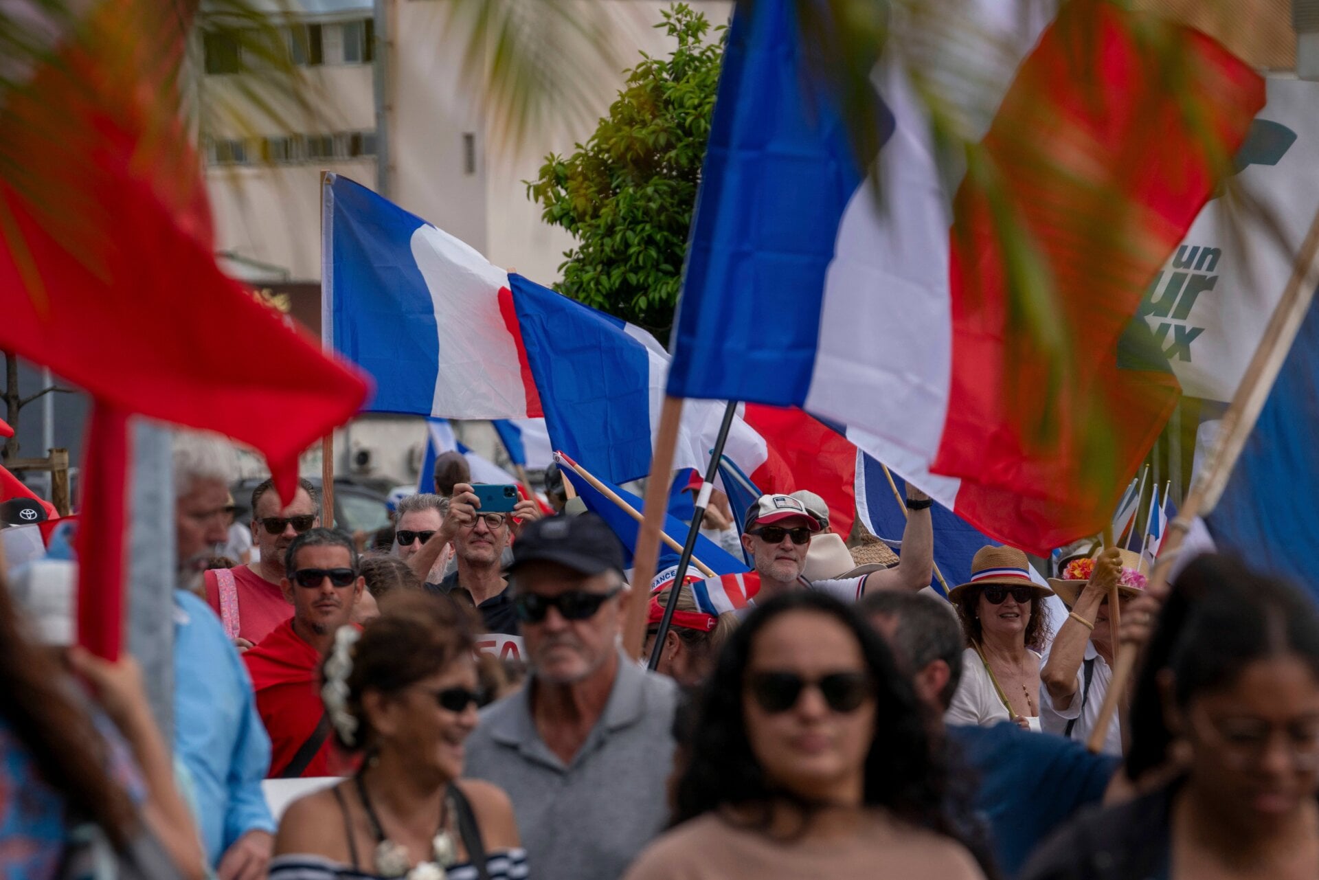Manifestantes de varios partidos leales ondean banderas nacionales francesas mientras marchan durante una manifestación para apoyar la ampliación del electorado para el próximas elecciones provinciales en Nueva Caledonia, en Noumea, el 13 de abril de 2024.