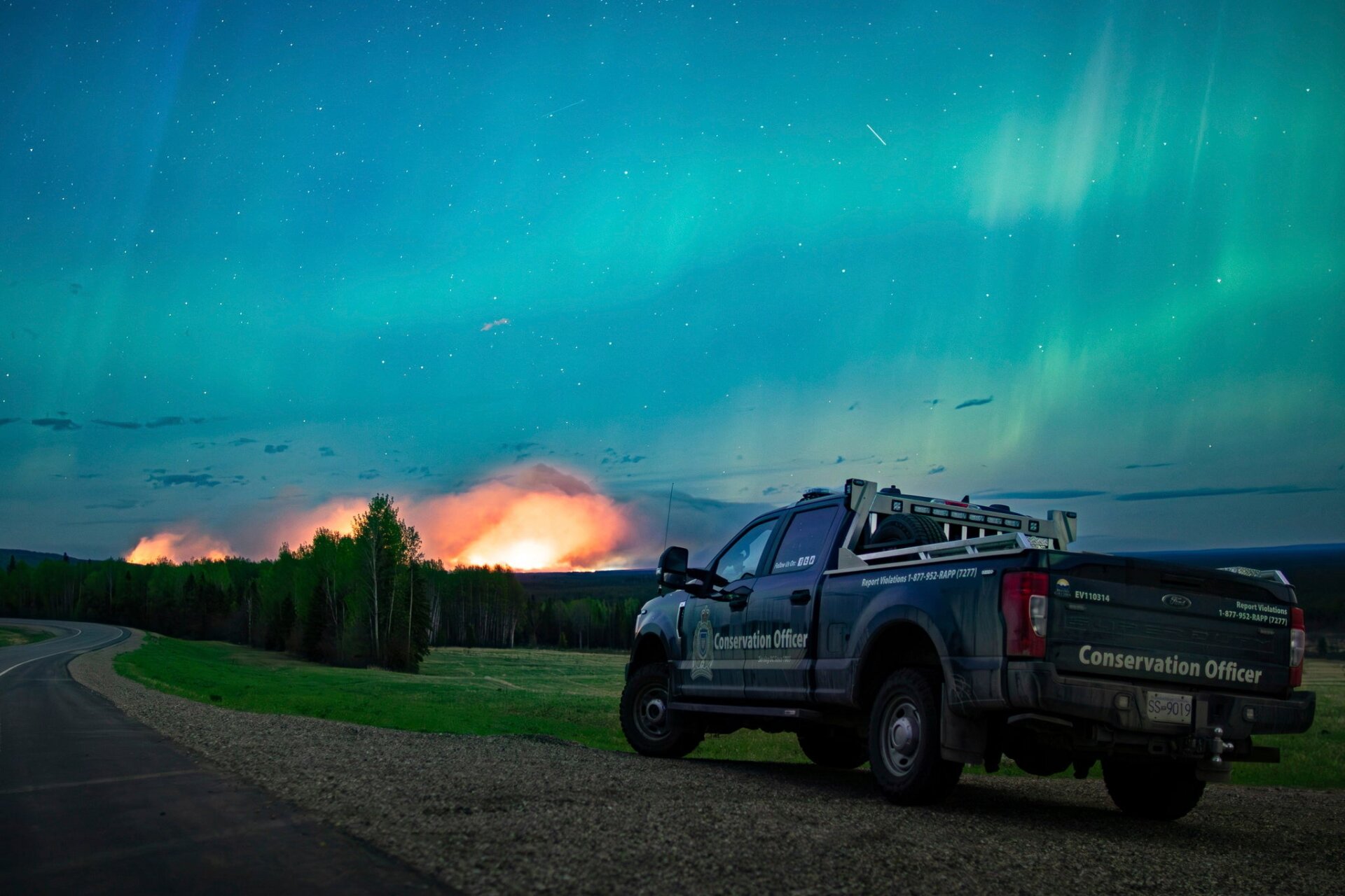 Esta foto proporcionada por el Ministerio de Agua, Tierra y Recursos muestra un incendio forestal, aurora boreal en lo alto, cerca de Fort Nelson, británico  Columbia sábado 11 de mayo de 2024. 