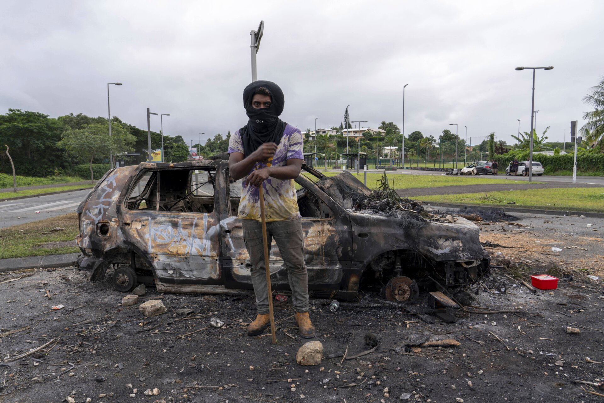 Un hombre en Nueva Caledonia se para frente a un automóvil quemado el 14 de mayo de 2024. 