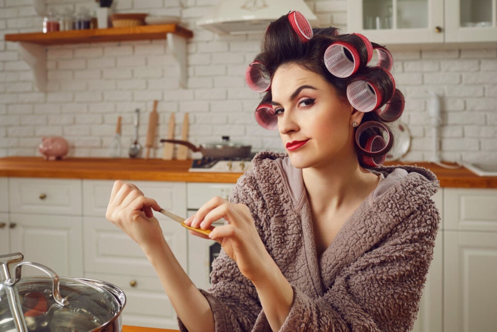 Beautiful,woman,wearing,makeup,,funny,hair,curlers,and,housecoat,sitting
